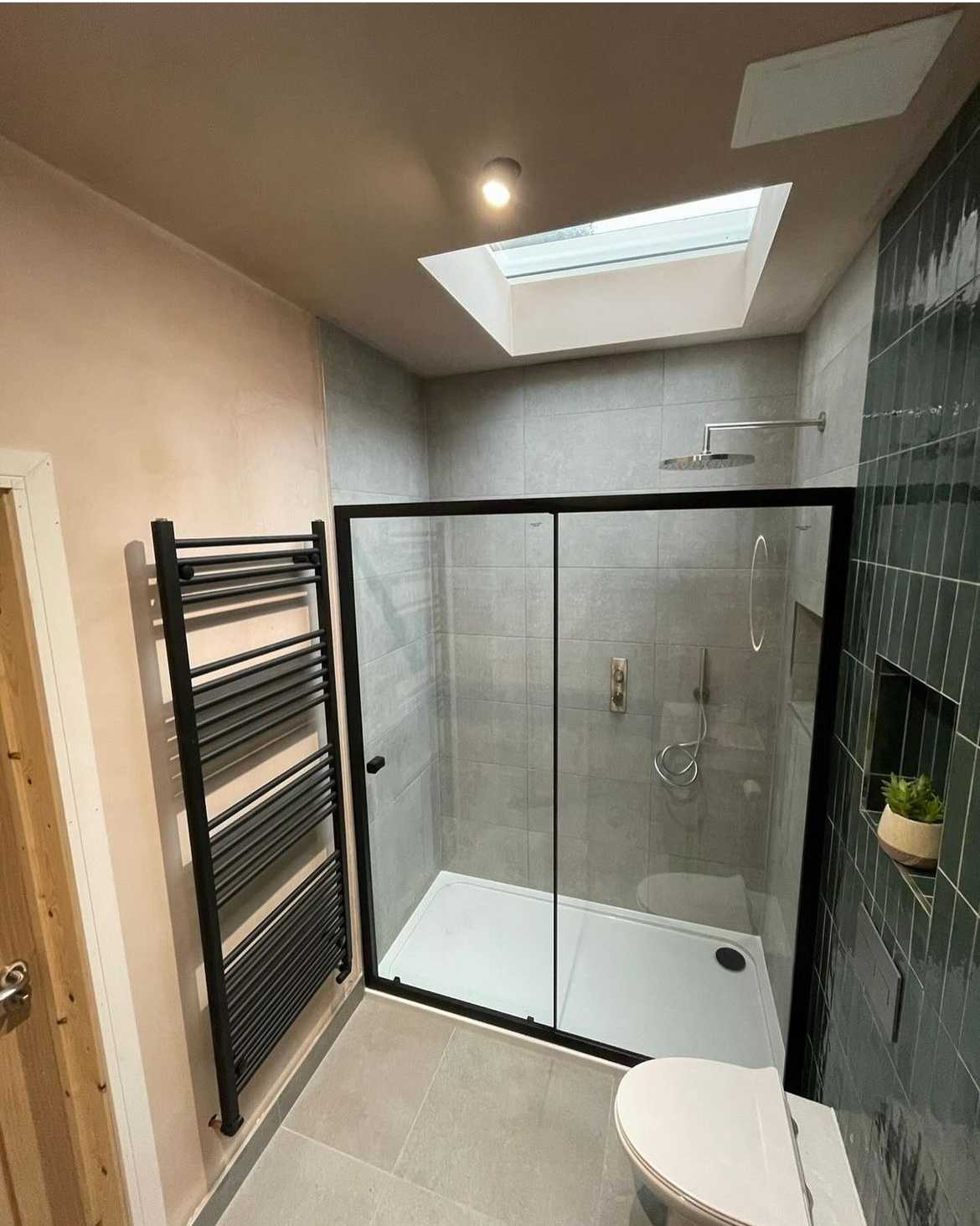 Walk-in shower enclosure with black towel radiator and rooflight
