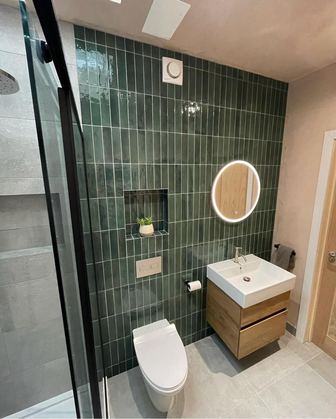 Green tiled shower room with wall hung WC, oak vanity and tiled niche