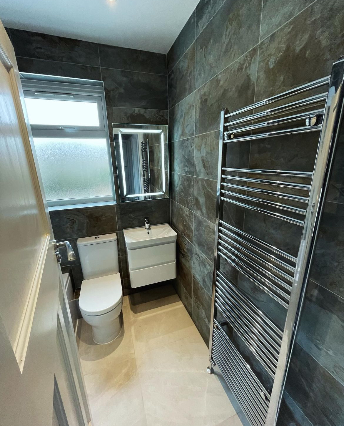 Slate tiled bathroom with wall hung vanity, WC and chrome towel radiator