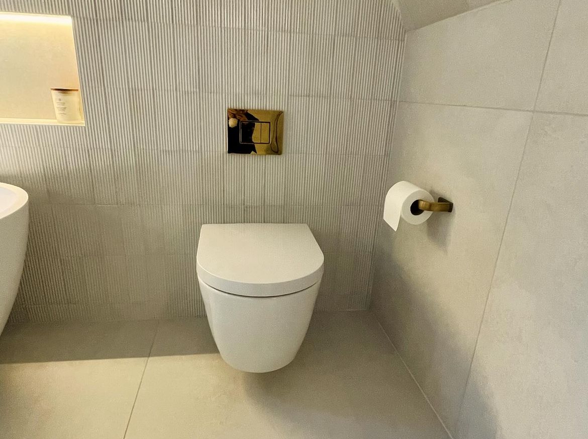 Wall hung WC with brushed brass flush plate and fluted tiling